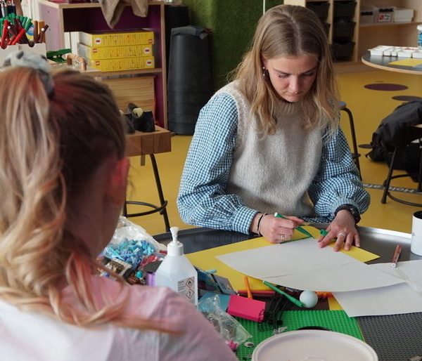 To elever, der sidder med materialer såsom papir og piberensere, som man kan bygge ting med