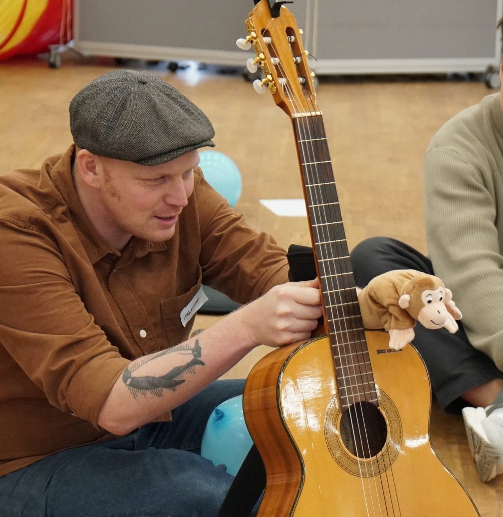 En pædagog med en guitar og en abe, som han taler igennem
