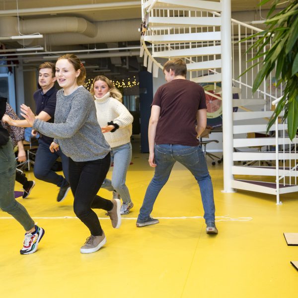 Students in movement during a teaching situation in PlayLab. In the back you can find the staircase, which is referred to in the booklet